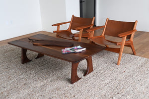 Wooden coffee table with two chairs in a minimalistic room.