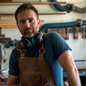 Man wearing a brown leather apron in a workshop setting