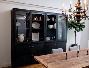 Dining room with black glass-fronted cabinet, wooden table, and chandelier.