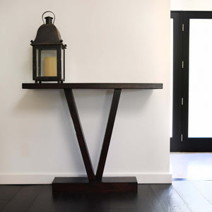 V-shaped wooden entry way table in hallway with lantern on top
